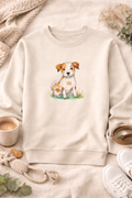 Beige sweatshirt with a dog illustration on a soft surface with a cup and shoes.
