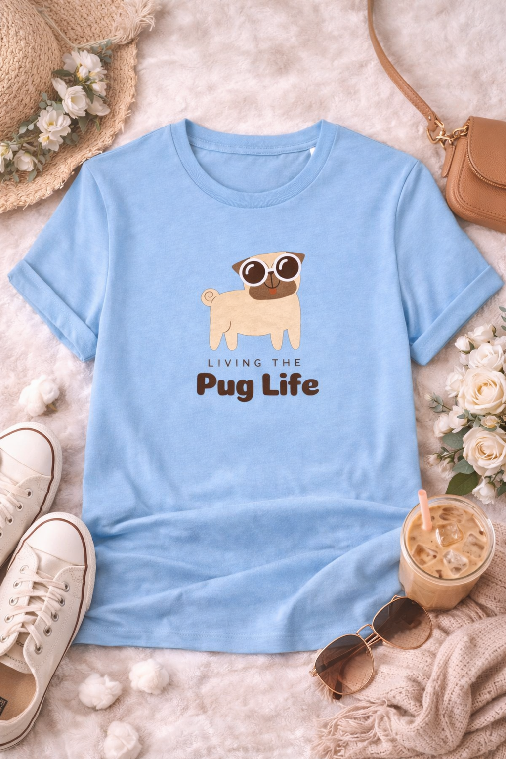 Light blue t-shirt with pug graphic and 'Living the Pug Life' text, placed on a textured surface with accessories.
